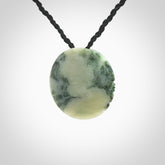 This piece is a small oval round, disc pendant hand carved in New Zealand jade.